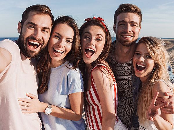 Eine Freundesgruppe macht voller Freude ein Selfie am Strand